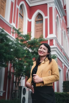 Beautiful asian woman (LGBTQ) natural makeup wear fashion yellow leather clothes with glasses posing at old town and vintage building outdoor fashion style