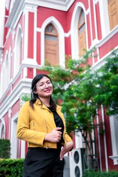 Beautiful asian woman (LGBTQ) natural makeup wear fashion yellow leather clothes with glasses posing at old town and vintage building outdoor fashion style