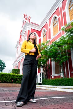 Beautiful asian woman (LGBTQ) natural makeup wear fashion yellow leather clothes with glasses posing at old town and vintage building outdoor fashion style