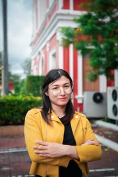 Beautiful asian woman (LGBTQ) natural makeup wear fashion yellow leather clothes with glasses posing at old town and vintage building outdoor fashion style