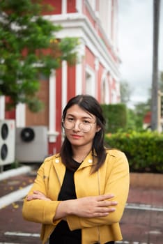 Beautiful asian woman (LGBTQ) natural makeup wear fashion yellow leather clothes with glasses posing at old town and vintage building outdoor fashion style