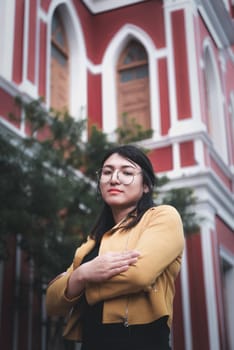 Beautiful asian woman (LGBTQ) natural makeup wear fashion yellow leather clothes with glasses posing at old town and vintage building outdoor fashion style