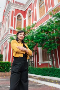 Beautiful asian woman (LGBTQ) natural makeup wear fashion yellow leather clothes with glasses posing at old town and vintage building outdoor fashion style