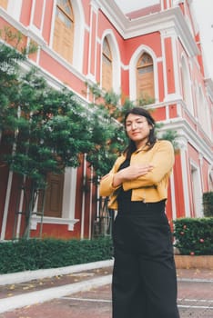 Beautiful asian woman (LGBTQ) natural makeup wear fashion yellow leather clothes with glasses posing at old town and vintage building outdoor fashion style