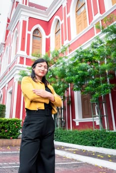 Beautiful asian woman (LGBTQ) natural makeup wear fashion yellow leather clothes with glasses posing at old town and vintage building outdoor fashion style