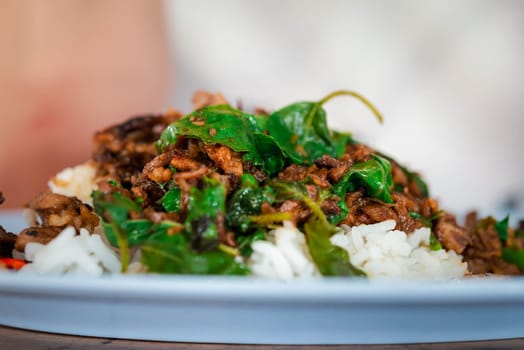 Rice topped with stir-fried pork or beef and basil for sale at Thai street food market or restaurant in Bangkok Thailand