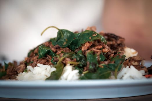 Rice topped with stir-fried pork or beef and basil for sale at Thai street food market or restaurant in Bangkok Thailand