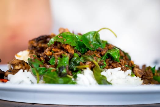 Rice topped with stir-fried pork or beef and basil for sale at Thai street food market or restaurant in Bangkok Thailand