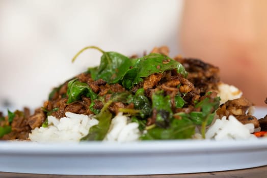 Rice topped with stir-fried pork or beef and basil for sale at Thai street food market or restaurant in Bangkok Thailand