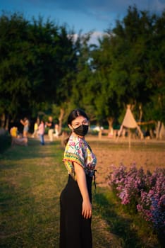 Beautiful asian woman (LGBTQ) natural makeup wear fashion relax clothes posing at nature of flower park or flower garden field lush growing for travel popular landmark in asia outdoor fashion style