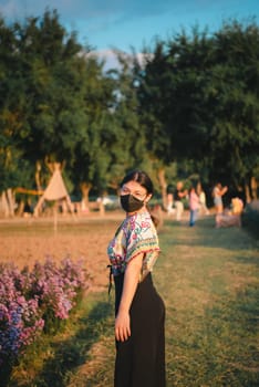 Beautiful asian woman (LGBTQ) natural makeup wear fashion relax clothes posing at nature of flower park or flower garden field lush growing for travel popular landmark in asia outdoor fashion style