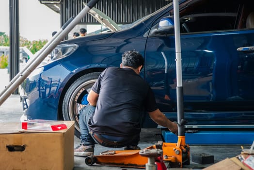 Car mechanic or serviceman disassembly and checking a disc brake and asbestos brake pads for fix and repair problem at car garage or repair shop