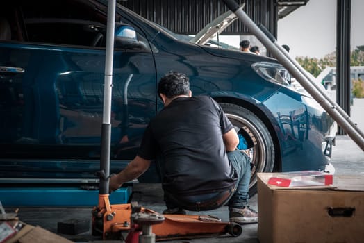 Car mechanic or serviceman disassembly and checking a disc brake and asbestos brake pads for fix and repair problem at car garage or repair shop