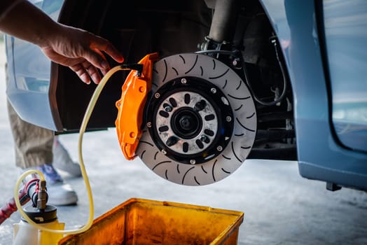 Car mechanic or serviceman disassembly and checking a disc brake and asbestos brake pads for fix and repair problem at car garage or repair shop