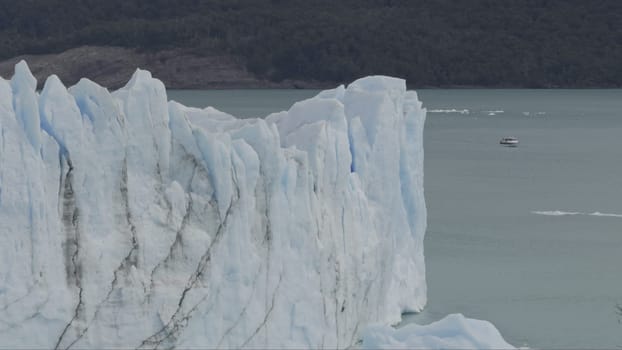 Tour boat approaches Perito Moreno Glacier's high ice cliffs in a remote adventure.