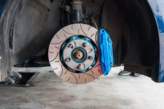 Car mechanic or serviceman disassembly and checking a disc brake and asbestos brake pads for fix and repair problem at car garage or repair shop