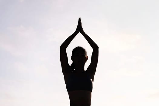 backlight of young woman doing yoga meditation, concept of mental relaxation and healthy lifestyle