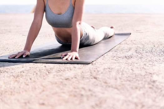 unrecognizable woman in sportswear doing yoga by the sea, concept of mental relaxation and healthy lifestyle, copy space for text