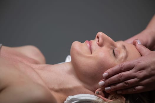 Caucasian woman undergoing head and face massage procedure