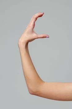 Female hand sign against gray background in studio close up