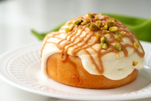 Cinnamon roll bun with icing on plate close up