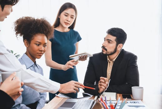 Multiracial analyst team use BI dashboard data to analyze financial report on meeting table. Group of diverse business people utilize data analysis by FIntech for success business marketing. Concord