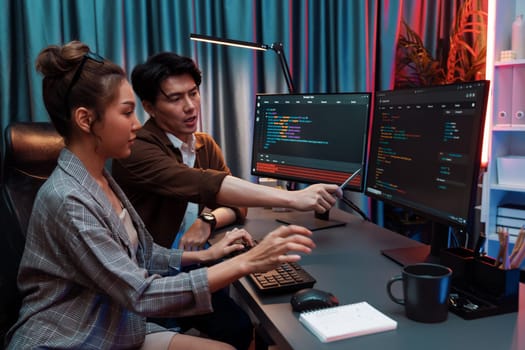 IT developers discussing with point to intelligent website development coder system running data online two screens information technology at neon light room at modern office. Infobahn.