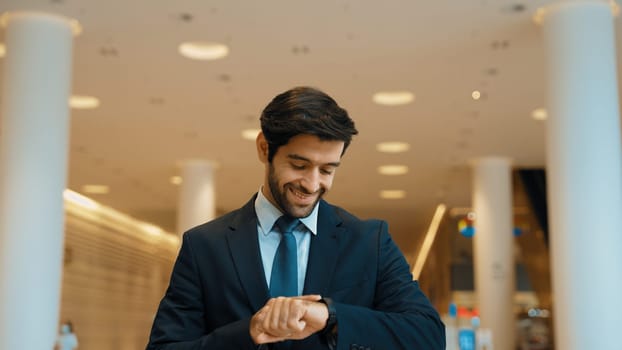 Caucasian smart business man looking at watch while waiting colleague. Executive manager wearing suit while standing at mall with blurred background. Investor wear blue suit check time. Exultant.