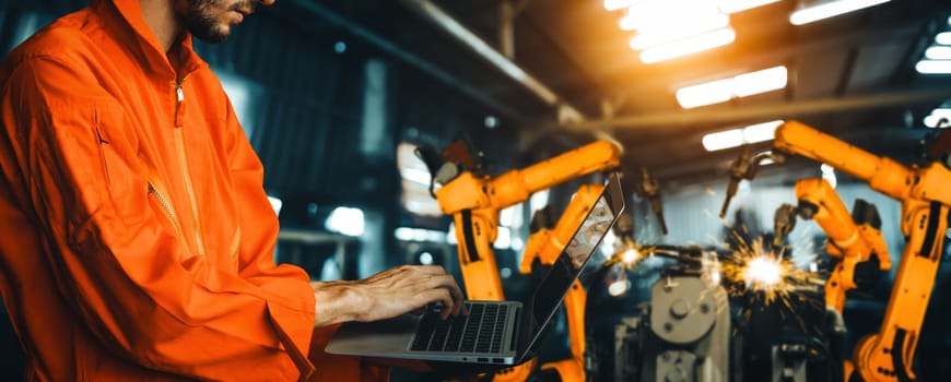 XAI Engineer use advanced robotic software to control industry robot arm in factory. Automation manufacturing process controlled by specialist using IOT software connected to internet network.