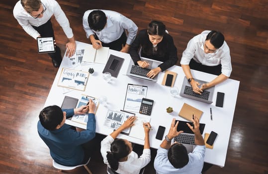 Top view analyst team utilizing BI Fintech to analyze financial data at table in meeting room. Analytic BI dashboard power on paper for business insight and strategic marketing planning. Prudent