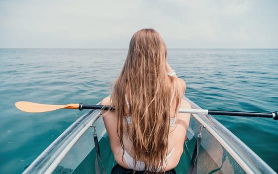 Woman in kayak back view. Happy young woman with long hair floating in transparent kayak on the crystal clear sea. Summer holiday vacation and cheerful female people having fun on the boat.