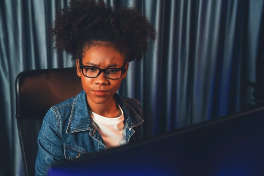 Young African American creator woman with serious face, thinking carefully and looking at final project document on laptop for planing next sequence. Concept of work at neat home place. Tastemaker.