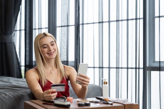 Young woman using online payment app and digital wallet on smartphone to pay with credit card. E commerce shopping and modern purchasing via mobile internet. Blithe