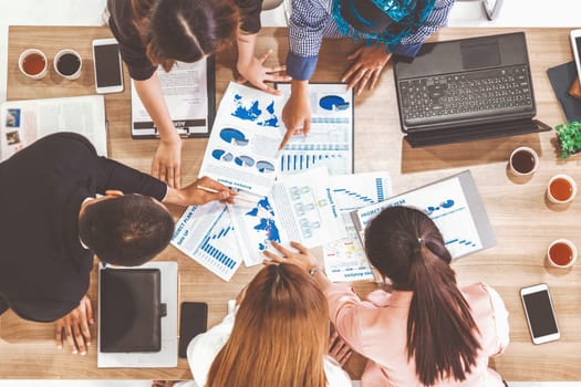 Top view of businessman executive in group meeting with other businessmen and businesswomen in modern office with laptop computer, coffee and document on table. People corporate business team uds