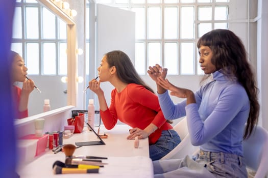 Young female friends putting on some professional makeup in dressing room. High quality 4k footage