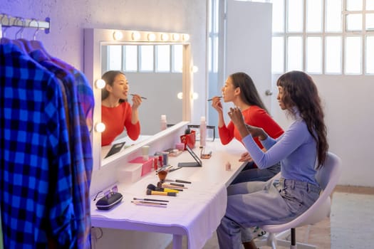 Pretty young female friends putting on some makeup before going out at night. High quality photo