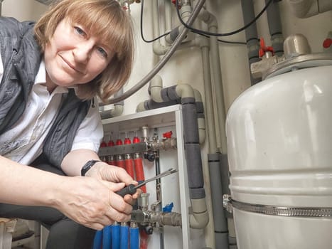 Female middle aged Technician Adjusting Industrial Water Filtration System. Woman services a water filtration unit and posing for photo or selfie