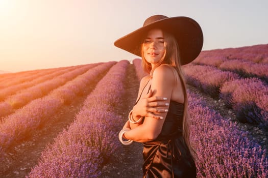 Close up portrait of young beautiful woman in a white dress and a hat is walking in the lavender field and smelling lavender bouquet.