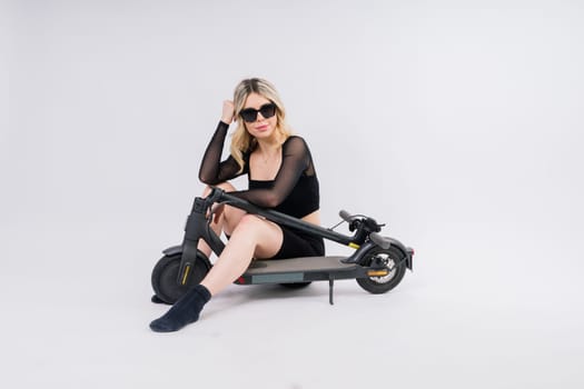 Full length profile shot of female on an electric scooter isolated on white and red background