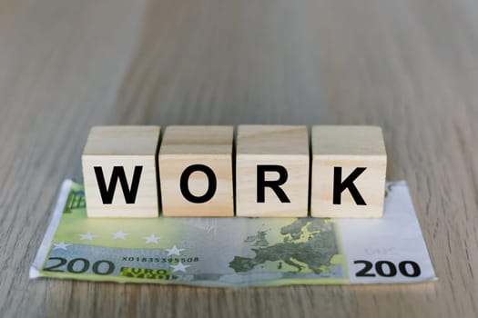 Work word on a wooden cubes blocks, money 200 Euro banknotes. Management big salary career concept.