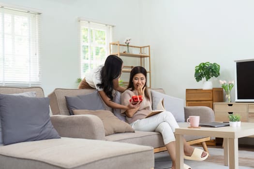 Congratulations. Loving asian mature daughter surprised mother with present in Mother's Day, giving her handmade card and gift box.