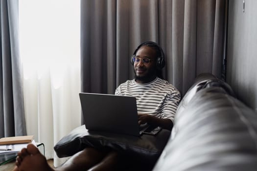 African American man relaxing on sofa and listening to music at home.