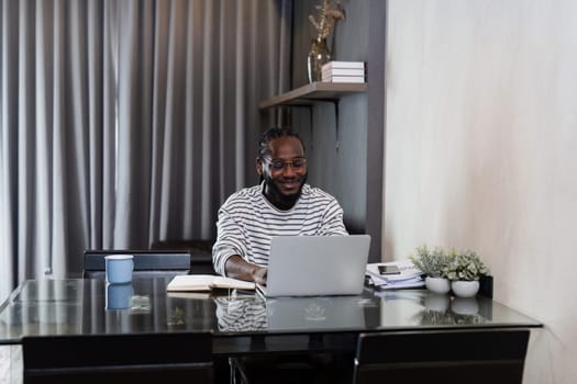 Young African American business man working with laptop and document on desk at home. work from home concept.