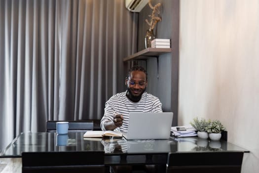 Young African American business man working with laptop and document on desk at home. work from home concept.