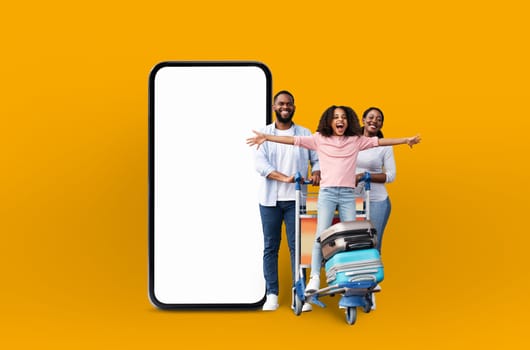 A cheerful african american family with suitcases next to a large phone screen, representing family vacation applications and online offers in a digital isolated manner