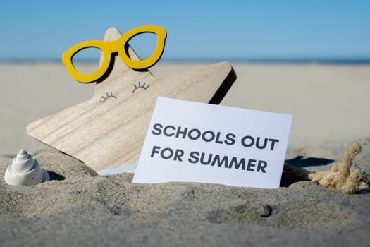 SCHOOLS OUT FOR SUMMER text on paper greeting card on background of funny starfish in glasses summer vacation decor. Sandy beach sun coast. Holiday concept postcard. Getting away Travel Business concept