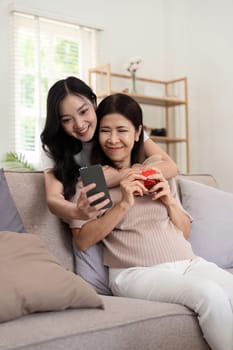 Daughter adult taking selfie using mobile phone with senior mother at home.