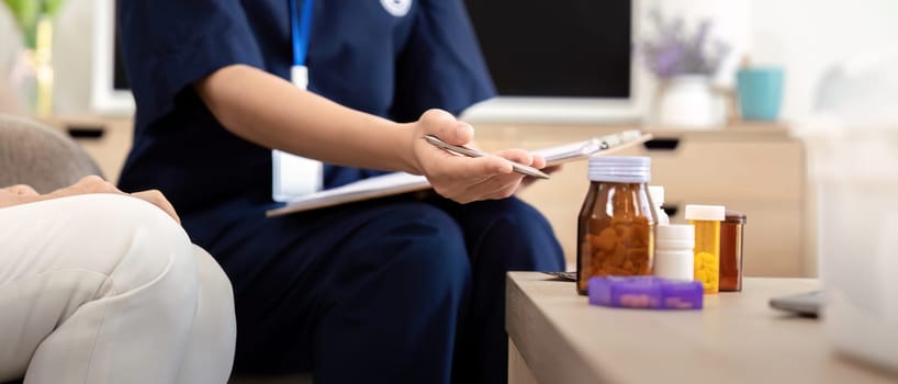 Caregiver woman hold medicine pill bottle, explain prescription to elderly old woman in living room in house.