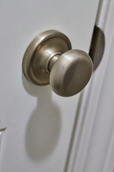 Close-up of a modern brushed nickel door knob on a white door, displaying a minimalist design, shot in Fort Wayne, Indiana