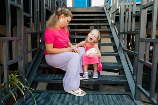 Blonde little girl with cochlear implant playing with her mother outdoor. Hear impairment deaf and health concept. Diversity and inclusion. Copy space.